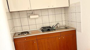 A small kitchen with a sink, a dish rack, and wooden cabinets. - Apartments Fortuna - Studio Apartment (Biograd na Moru)