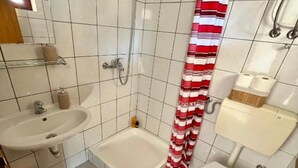 A bathroom with a shower, sink, toilet, and a striped shower curtain. - Apartments Fortuna - Studio Apartment (Biograd na Moru)