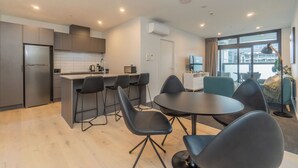 A modern kitchen with a central island, bar stools, and a dining table with chairs. - High End Centrally located apartment with carpark (Auckland)