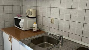 A compact kitchen with a microwave, a small sink, and a cabinet.