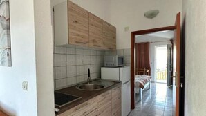 A compact kitchen with a wooden cabinet, a microwave, and a sink. - One bedroom apartment with balcony-APP4 (Podaca)