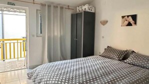 A bedroom with a bed, a wardrobe, a picture on the wall, and a balcony with a railing. - Apartments Natali - One Bedroom Apartment with Balcony (APP6) (Podaca)