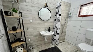 Une salle de bain moderne avec un lavabo blanc, un rideau de douche noir et blanc et un miroir rond.