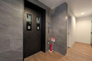An elevator with a digital display, a fire extinguisher, and a sign on the wall.