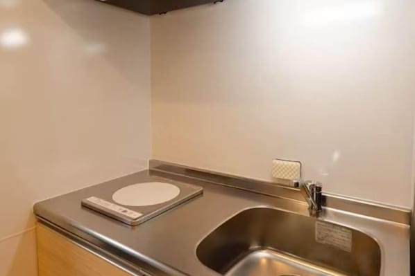 A stainless steel sink with a faucet and a scale on the countertop.