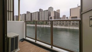 A balcony with a view of a river and buildings. - R Home Sakuragawa Riverside (Osaka)