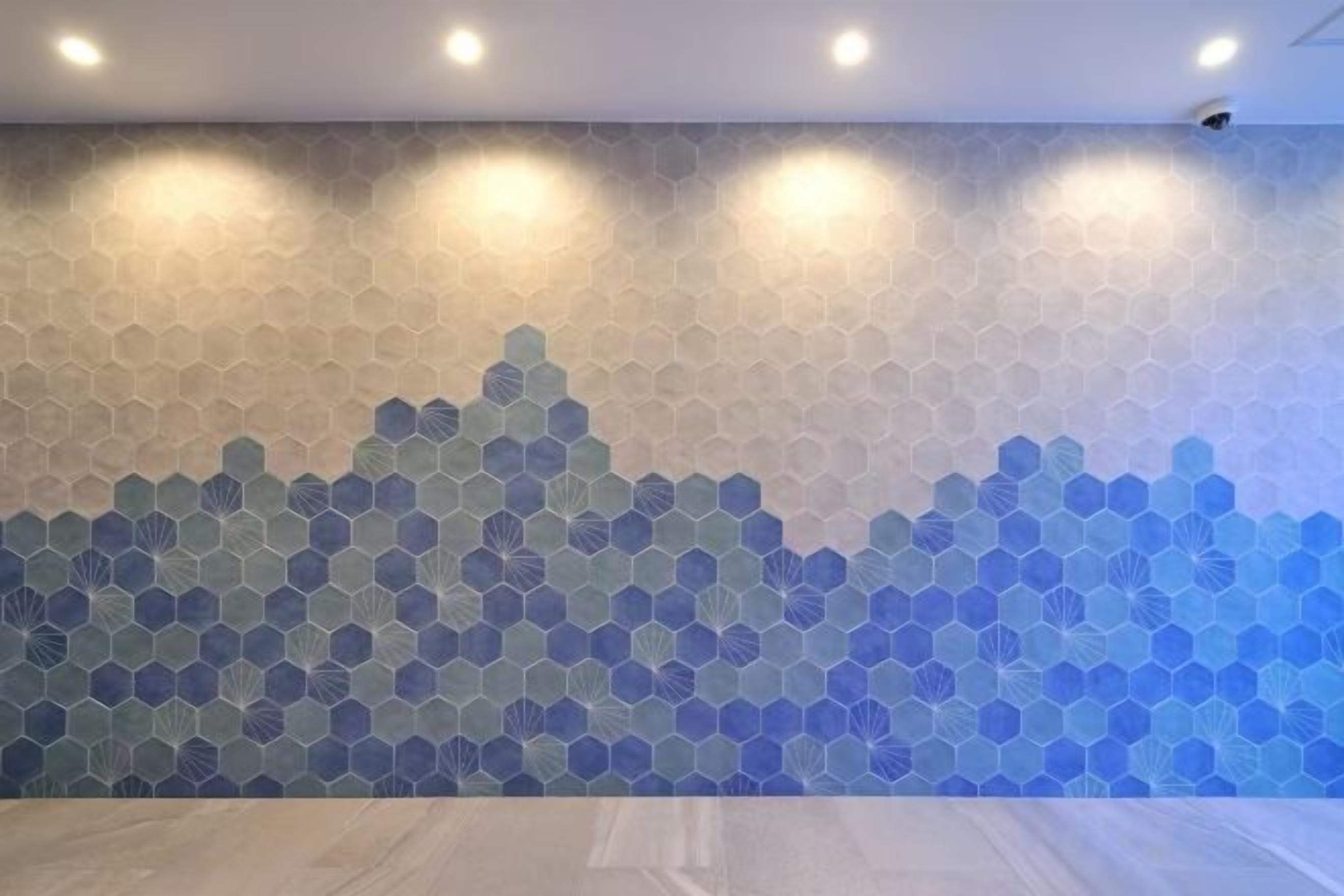 Een muur met een geometrisch patroon, inbouwverlichting en een beveiligingscamera.