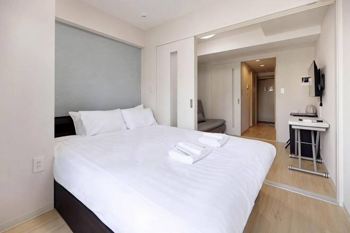 A hotel room with a large bed, a desk, a chair, and a TV.