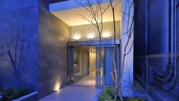 A modern building with a glass entrance, a pathway, and a small tree. - R Home Sakuragawa Riverside (Osaka)