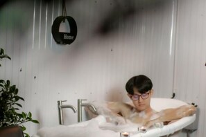 A person in a bathtub with a 'Home' sign on the wall. - The Haus at Khaokho (Khao Kho)