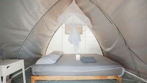 A tent with a bed, a small table, and a hanging mosquito net. - The Haus at Khaokho (Khao Kho)