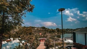 A pathway leading to a building with a view of a lake and hills in the background. - The Haus at Khaokho (Khao Kho)