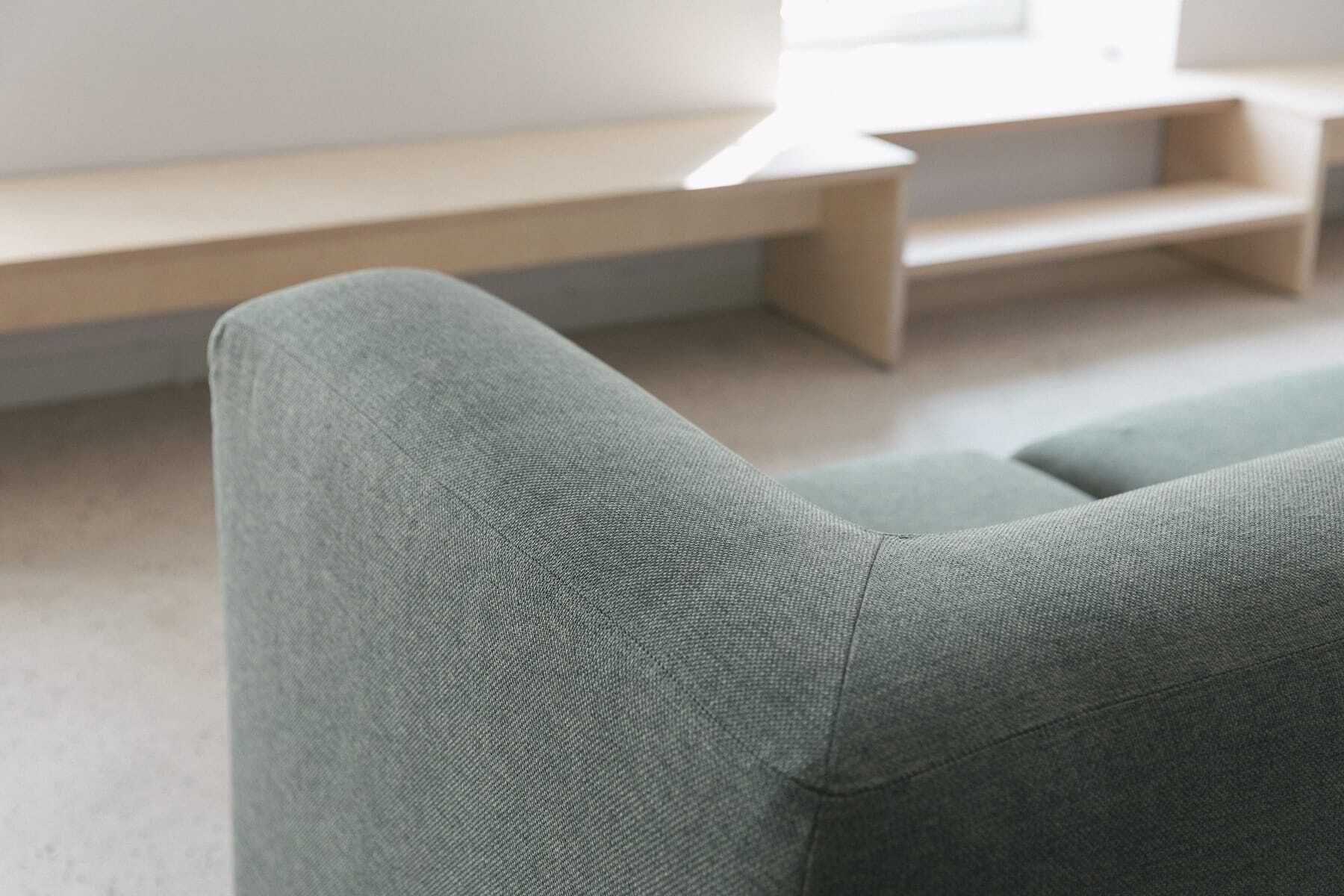 A section of a room with a grey upholstered chair and a wooden bench.