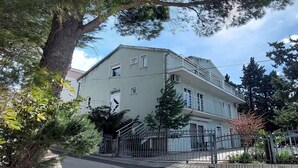 Un bâtiment à deux étages, doté d’une façade de couleur claire, d’une clôture en métal et d’un escalier menant à un niveau supérieur.