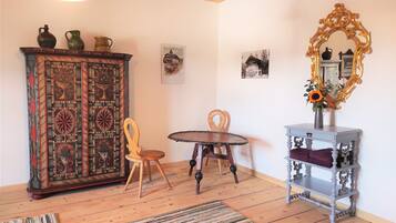 A room with a wooden cabinet, a table, a chair, a mirror, and a rug.