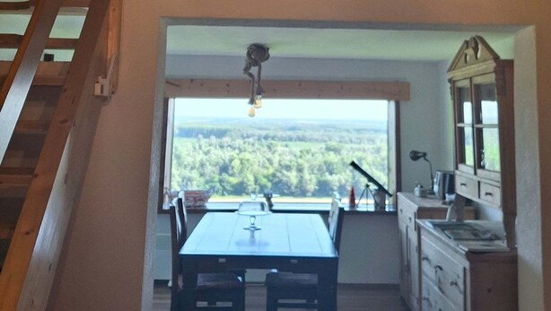 Eine Küche mit großem Fenster, Holztisch und Schränken.