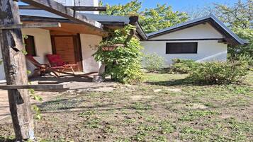 Una casa con una veranda in legno, una sedia rossa e un piccolo giardino.