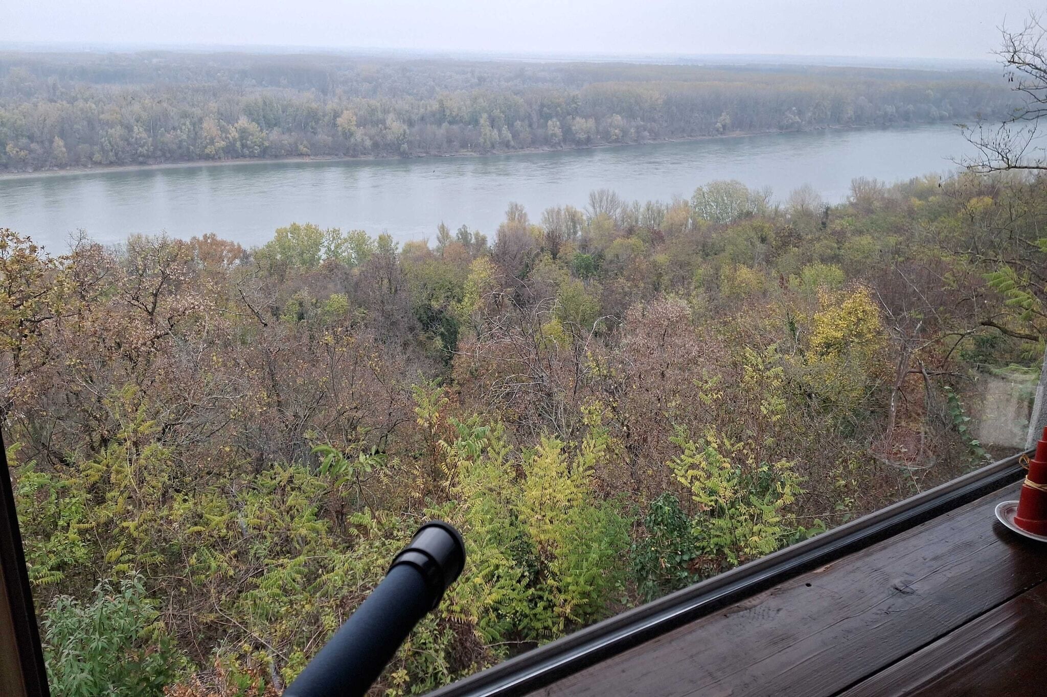 A view from a window overlooking a river and forested landscape.