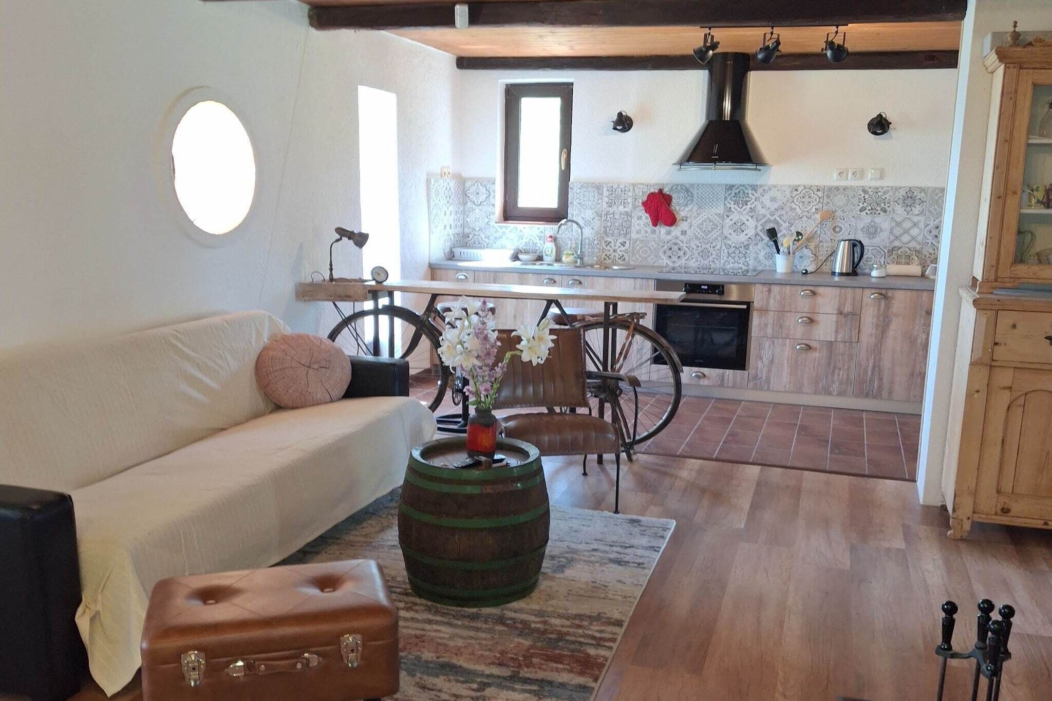 Ein Wohnzimmer mit einer Couch, einem Vintage-Fahrrad, einem Holzbottich und einem Koffer.