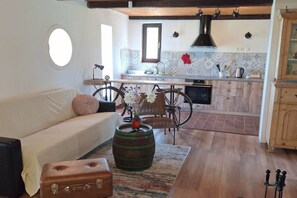 A living room with a sofa, a vintage bicycle, a wooden barrel, and a suitcase.