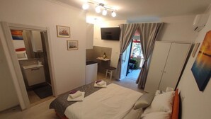 A hotel room with a bed, a desk, a chair, a wardrobe, and a bathroom.