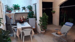 A small dining area with a table and chairs, surrounded by potted plants and a hanging plant. - Holiday home with parking and 2 rooms (Dubrovnik)