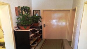 A narrow hallway with a wooden door, a potted plant, and a shelf with shoes. - Holiday home with parking and 2 rooms (Dubrovnik)