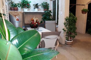 A small patio area with a table and chairs, surrounded by various potted plants and a hanging plant. - Holiday home with parking and 2 rooms (Dubrovnik)