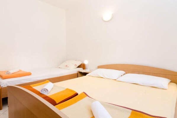 Una habitación de hotel con dos camas, un cabecero de madera y una mesita de noche con lámpara.