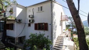 A two-story building with a balcony, air conditioning units, and a staircase leading to the upper floor.