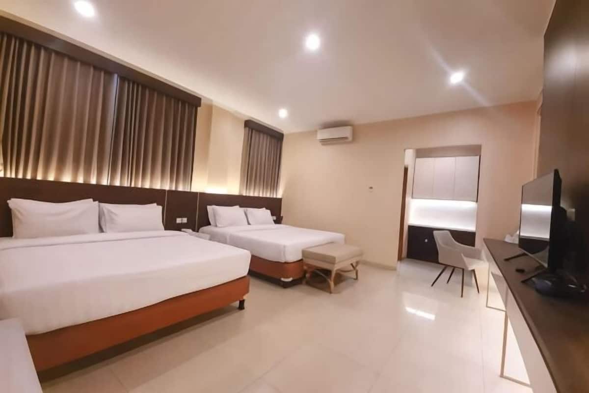 A hotel room with two beds, a desk, a chair, and a television.