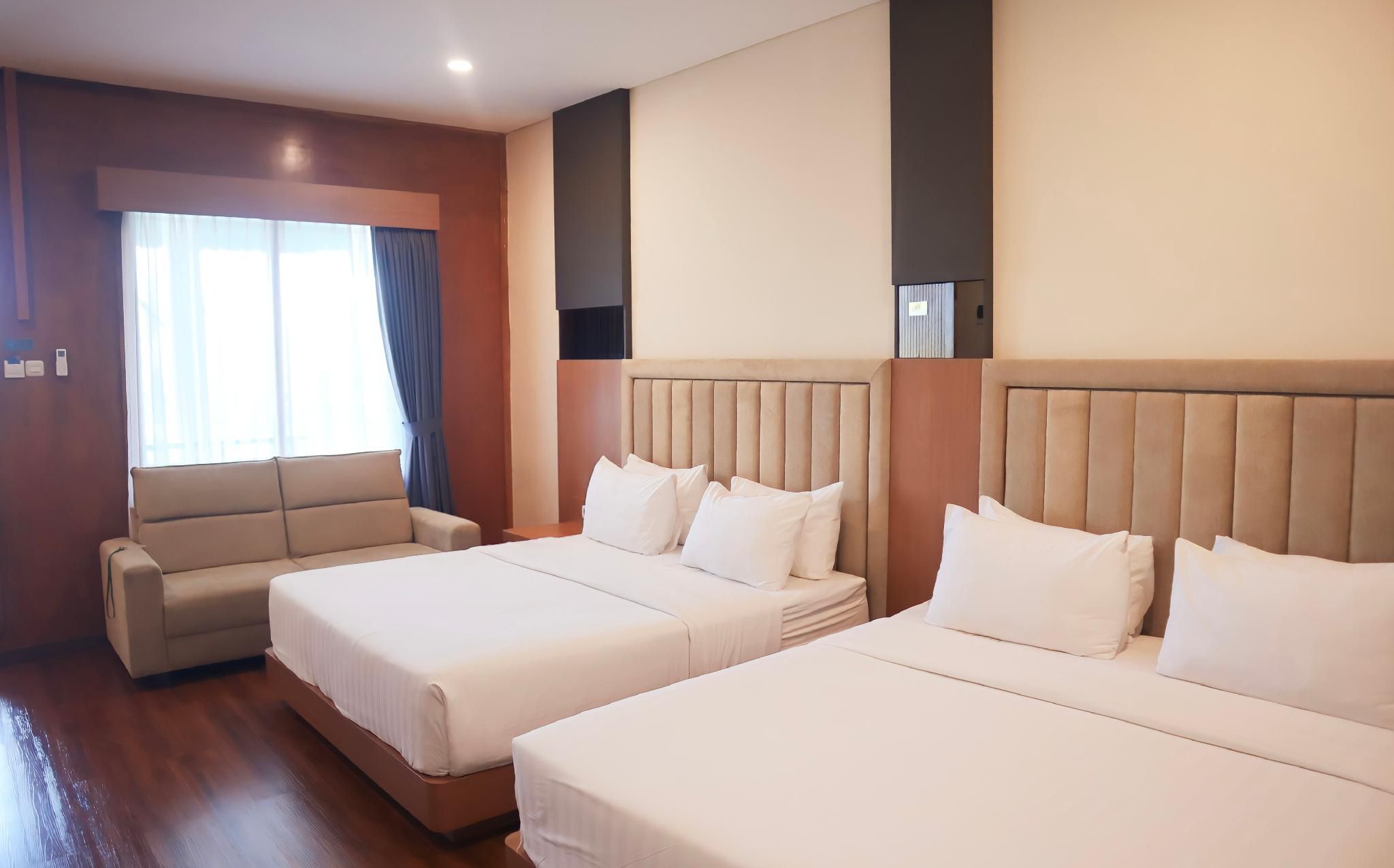 Habitación de hotel con dos camas, un sofá y una ventana con cortinas.