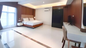 Una habitación de hotel moderna con una cama grande, mesitas de noche, un escritorio con silla y un espejo amplio.