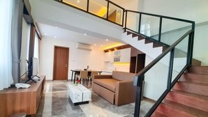 A modern living room with a sofa, coffee table, and a staircase.