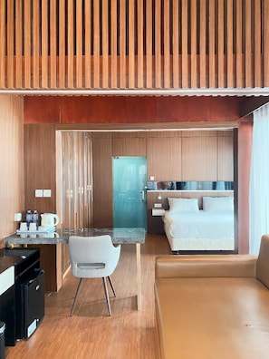 Een moderne hotelkamer met een kitchenette, een eethoek en een bed.