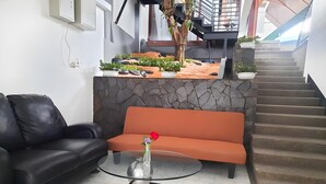 Un interior moderno con un sofá de cuero negro, un sofá naranja y una mesa de centro de vidrio con un florero.