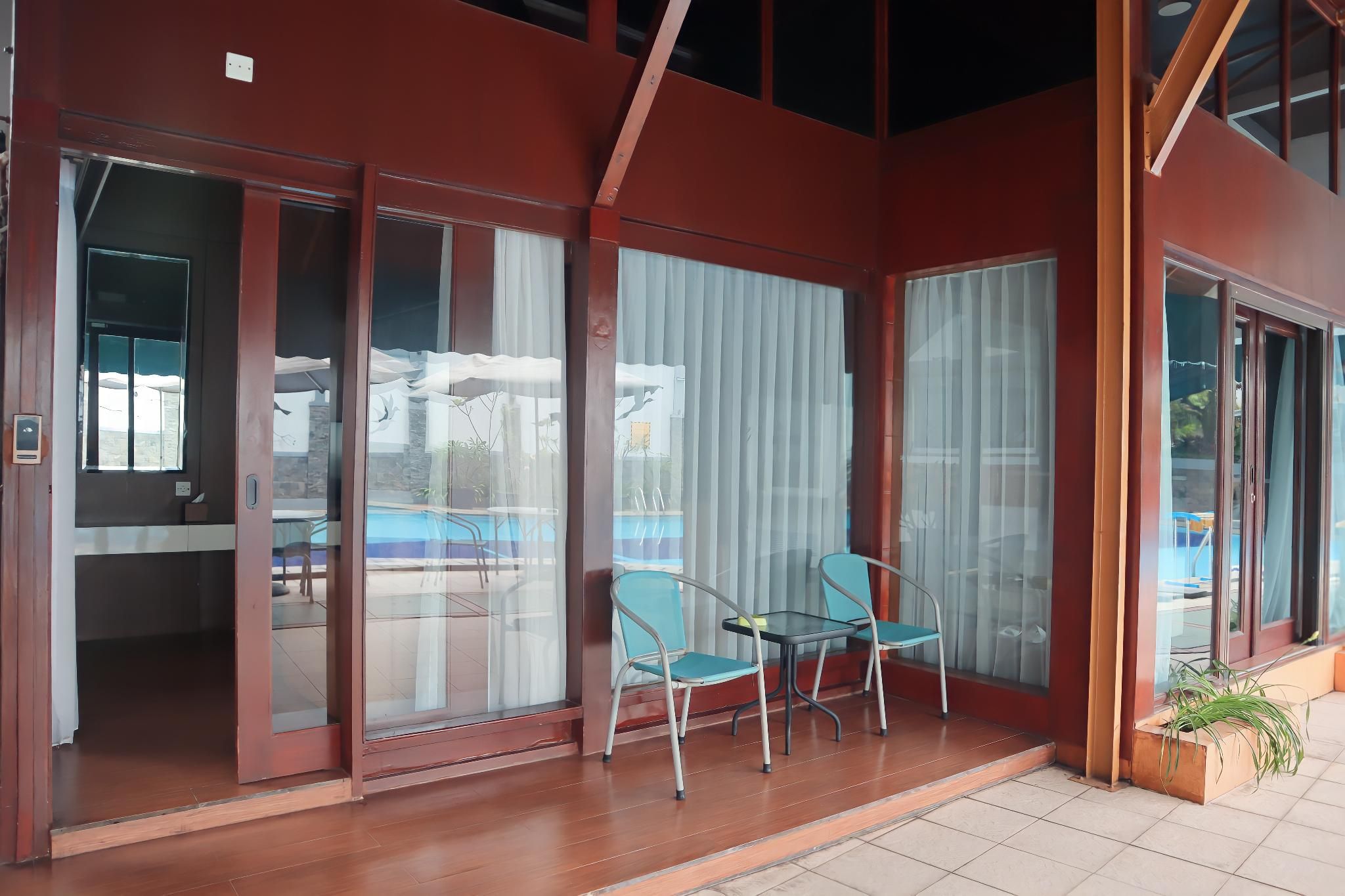 A modern building with large glass doors leading to a patio area with two chairs and a small table.