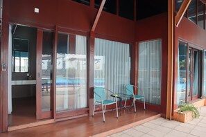 A modern building with large glass doors leading to a patio area with two chairs and a small table. - Shakti Villa Dago (Coblong)