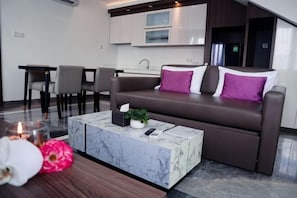 Un espacio de estar moderno con un sofá, una mesa de centro de mármol y una zona de comedor.