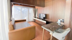 Un espacio moderno con sofá, televisión y una pequeña mesa.