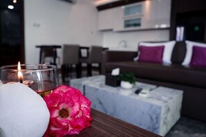 A modern living room with a marble coffee table, a glass candle holder, and a pink flower. - Shakti Villa Dago Bandung (Coblong)
