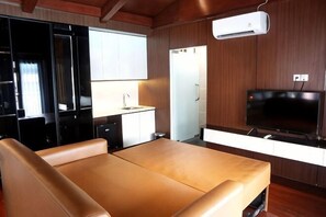 Una habitación con cama, televisión, kitchenette y baño.