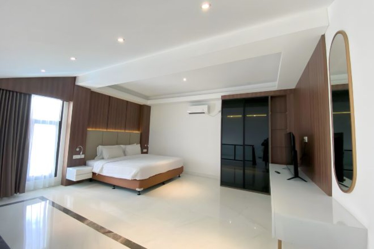 Una habitación de hotel moderna con una cama grande, un televisor de pantalla plana y un vestidor.