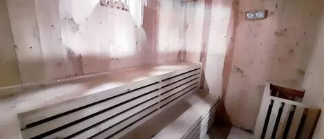Una habitación con un banco de madera, un radiador y una pequeña mesa.