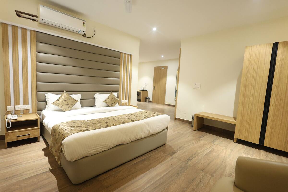 A hotel room with a large bed, bedside tables, a wardrobe, and a bench.