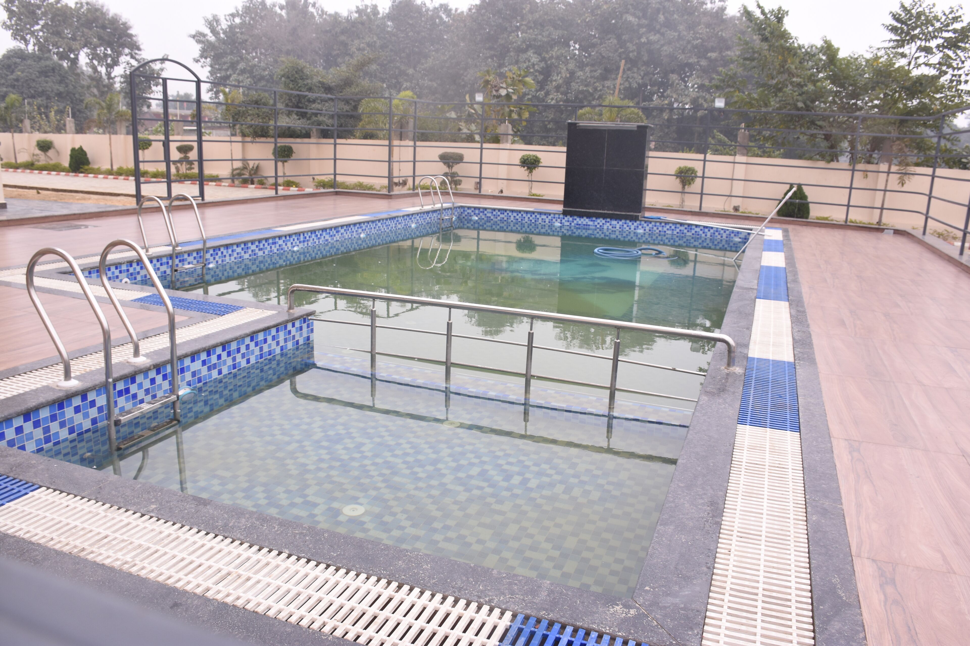 A swimming pool with a tiled edge, a metal ladder, and a safety railing.