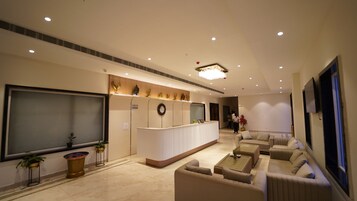 Un moderno vestíbulo de hotel con mostrador de recepción, zona de estar y una gran televisión de pantalla plana.