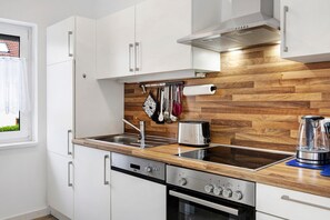 Une cuisine moderne avec des meubles blancs, un pare-feu en bois, des appareils en acier inoxydable et une fenêtre offrant une belle vue.