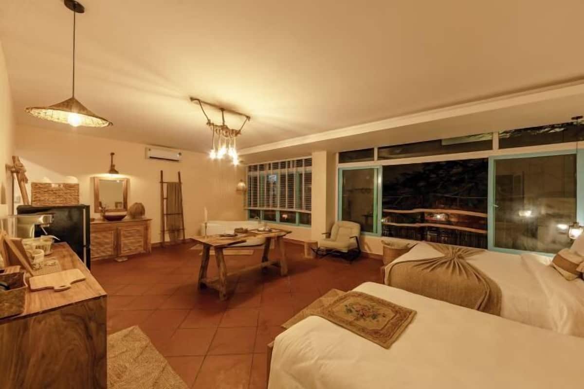 A room with a bed, a desk, a chair, a table, and a window with a view.