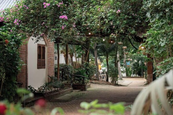 A covered pathway leading to a building with a brick facade and a small porch area. - Canaan Beach Home (Phu Quoc Island)
